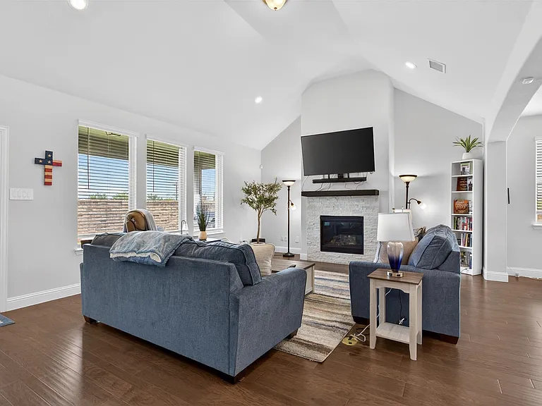 Bright living area featuring wood-finish flooring, a vaulted ceiling, and recessed lighting