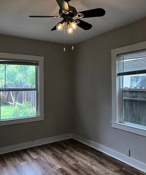 This is the bedroom that faces the backyard. The windows let in ample natural light. There is a ceiling fan and wood laminate flooring.