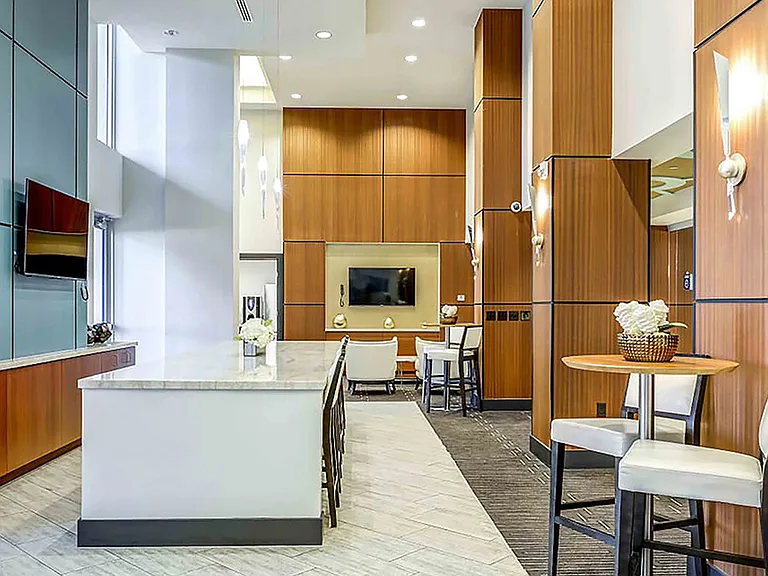 Luxury apartment resident lounge with kitchen island, bar seating, and modern fireplace
