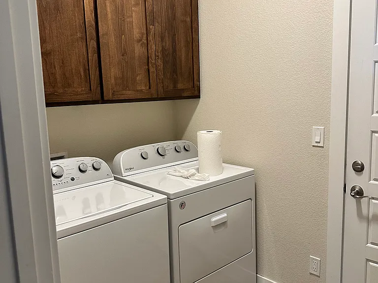 Laundry room off kitchen with washer and dryer. Extra cabinets for laundry needs or storage.