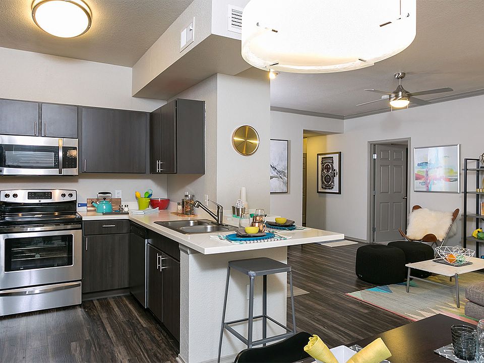 Apartment Kitchen with Stainless Steel Appliances, Dining and Living Room with wood floors.