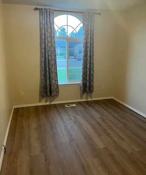 Bedroom one with waterproof flooring and arched window.