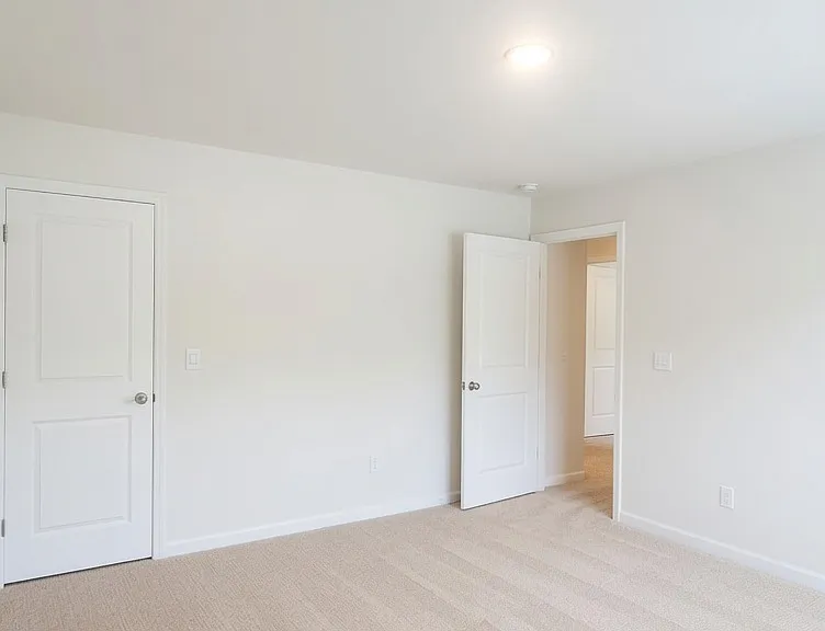 The second bedroom with soft neutral carpet, high ceilings, recessed lighting, and multiple closets. Excellent natural light potential and generous wall space for furniture placement.