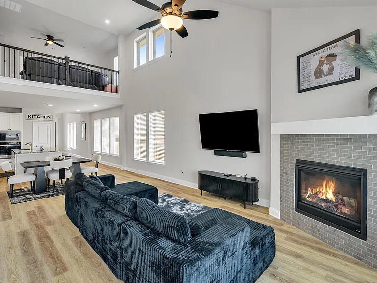 Spacious living area featuring high ceilings, light wood-finish flooring, and multiple windows