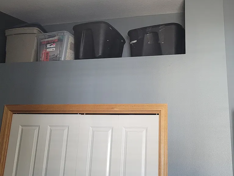 Bedroom closet and ledge w/ storage bins.