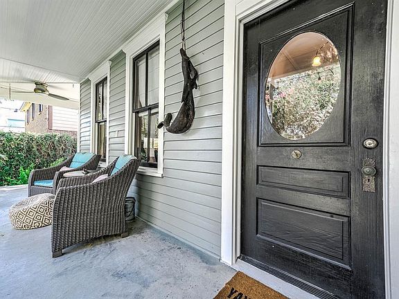 A look at this lovely covered front porch shows a large dark stained wooden door with glass detailing. This front porch is large and offers so much space for intimate conversations and world watching.