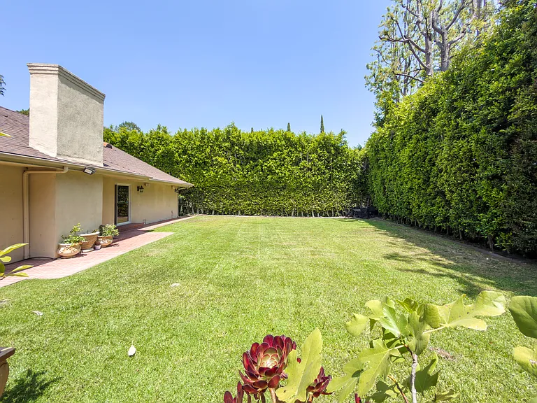Flowering garden borders and a tall hedge wall create a private green retreat at this Beverly Hills luxury rental, 1094 Garden Lane, 90210.