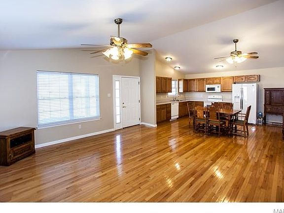 Family room open to kitchen with ceiling fans and vaulted ceilings.