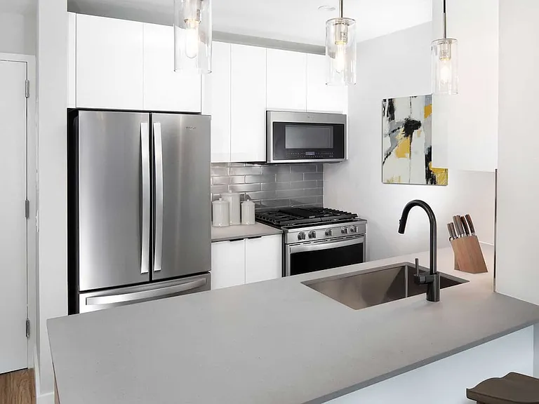 Renovated Package I kitchen with quartz stone countertop, tile backsplash, and stainless steel appliances