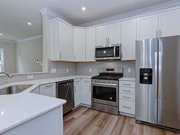 Kitchen with upgraded quartz countertops, subway tile backsplash, stainless steel appliances, bar seating and seperate pantry