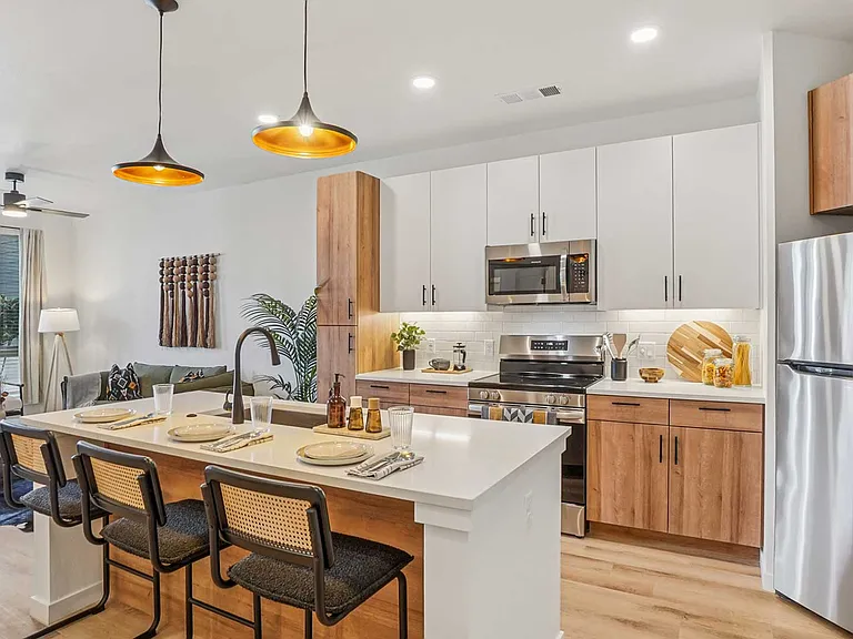 Open-concept interiors feature quartz countertops, stainless steel appliances, and warm modern finishes designed for everyday comfort.