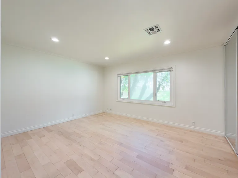 Unfurnished secondary bedroom with a leafy tree-lined window view offers a peaceful retreat in this Beverly Hills luxury rental at 1094 Garden Lane, 90210.