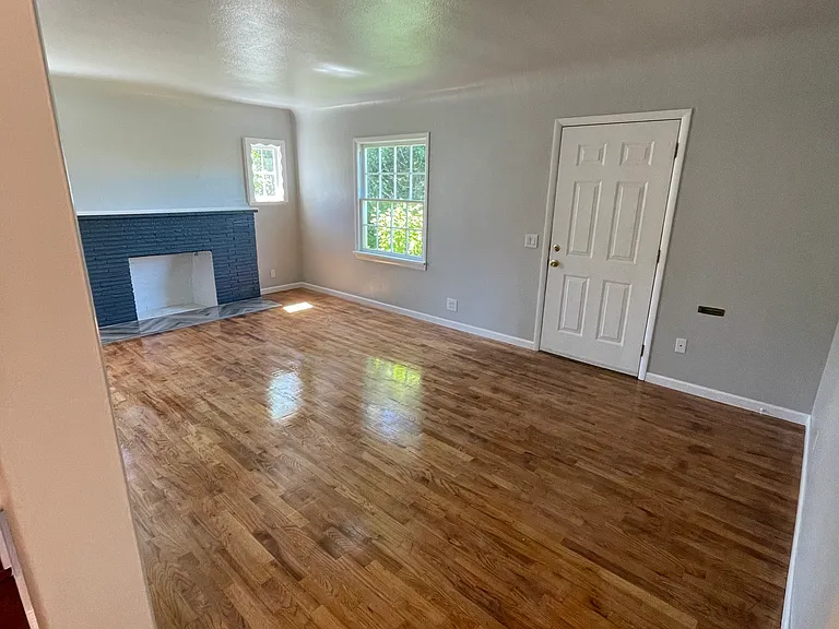Living room: Access to street parking, kitchen and hallway leading to main level bath and bed. Also steps leading upstairs.