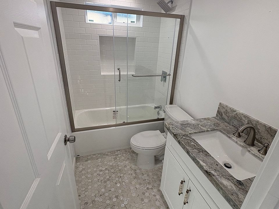 Tub Shower, full height tile in the tub shower and a Delta sliding shower door, Countertop Material Ocean Fantasy. American Standard quality toilet.