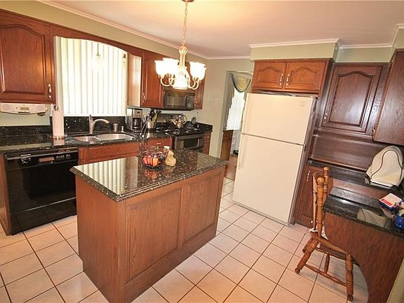 Enjoy cooking in this gourmet kitchen with warm wood cabinetry, granite counters kitchen island, built in desk, appliance garage