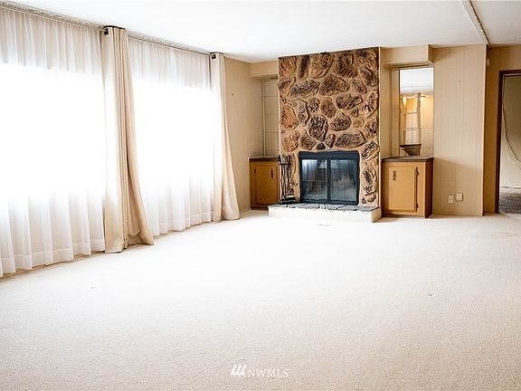 Well lit living room with wood burning fireplace and built-ins.