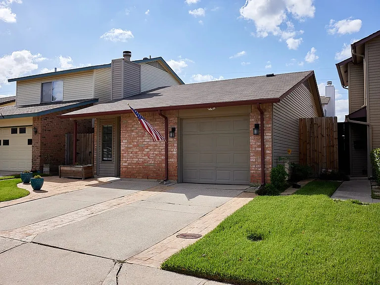 View of front of property featuring brick siding, driveway, a garage, a chimney, and a shingled roof