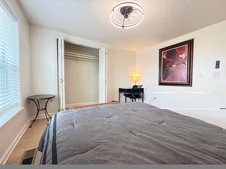 Furnished bedroom with a comfortable bed, dedicated desk space, and a closet for easy storage.