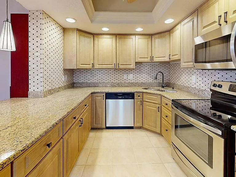 Modern kitchen with granite countertops, stainless steel appliances, and elegant pendant lighting, offering a stylish and functional cooking space.