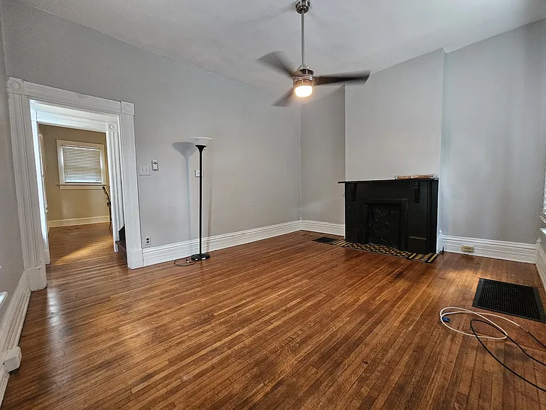 View of the living room from the front entrance. Large ceilings, rustic wooden floors and a marble decorative fireplace.