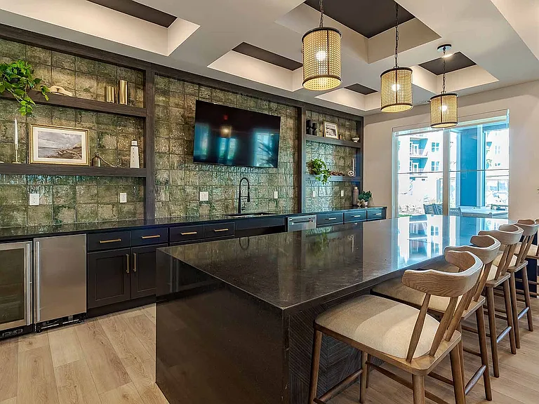 Host with ease in the clubhouse kitchen, featuring an oversized island, bar seating, and a striking tile backsplash perfect for entertaining.