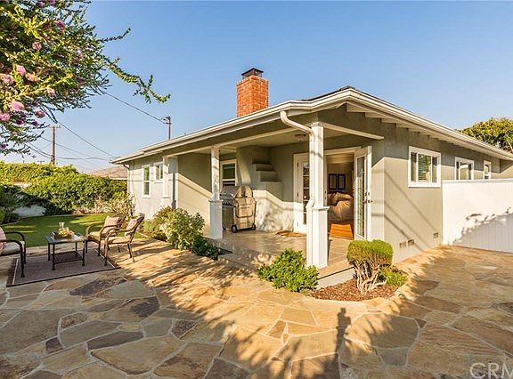 Gorgeous backyard with covered porch and stone patio plus turf grass for easy maintenance