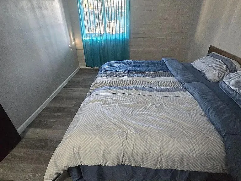 Spacious room with , easy-care flooring, and a large window with curtains for natural light and privacy. Desk, chair.