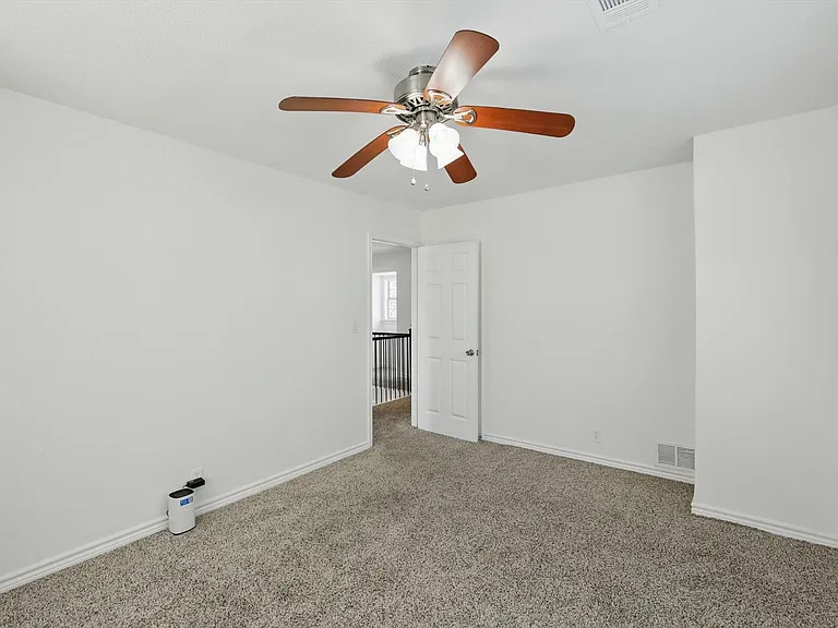 Empty room featuring carpet, a ceiling fan, and baseboards