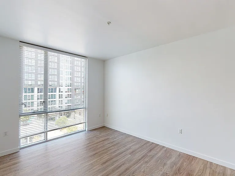 Apartment living room with wood-style flooring and floor-to-ceiling windows.