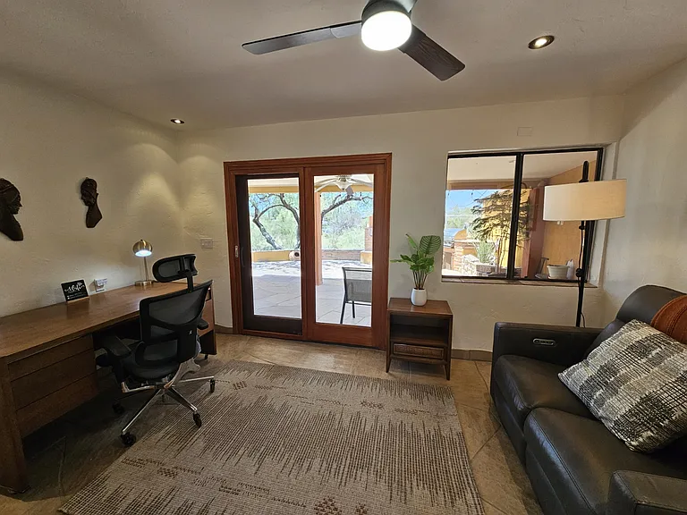 Dedicated office space. Executive desk, X-Chair, and a power reclining loveseat. Sliders go to side patio with outdoor fireplace and gas grill.