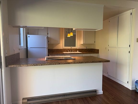 Kitchen area with glass top electric range, new refrigerator, freshly painted white cabinets, double sink, dishwasher