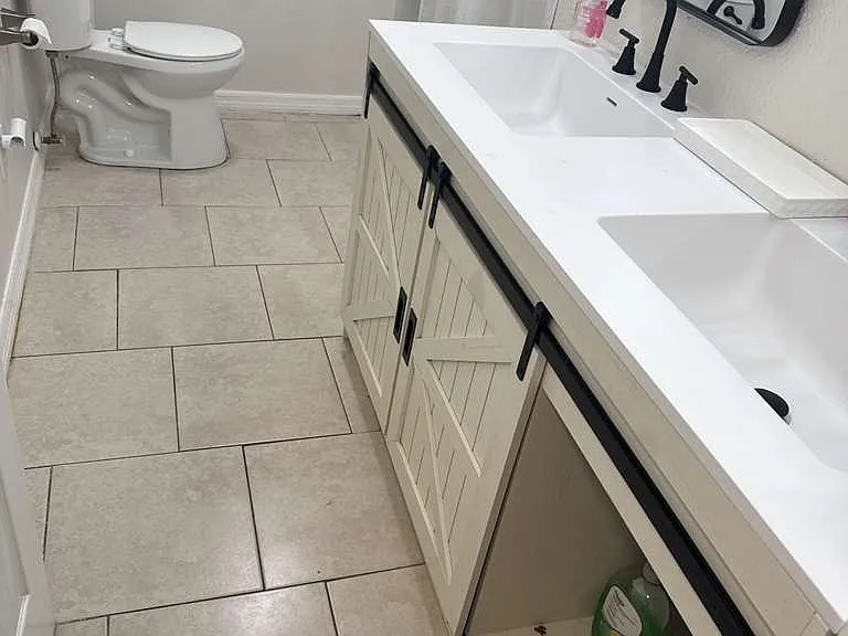 Clean bathroom vanity with white cabinetry and generous mirror space.