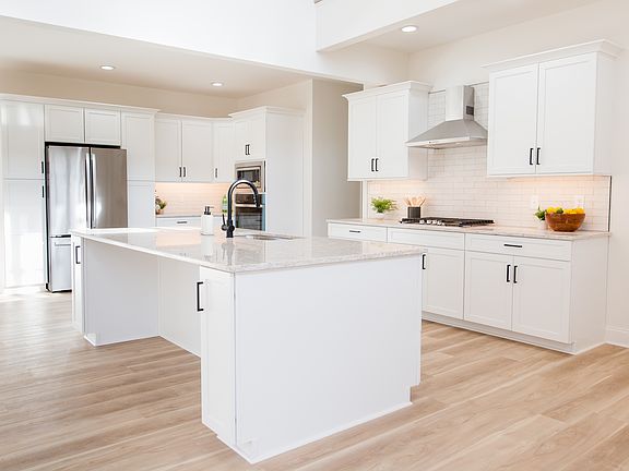 Custom kitchen with oversized island, gas cook top, stone counters, tile backsplash more