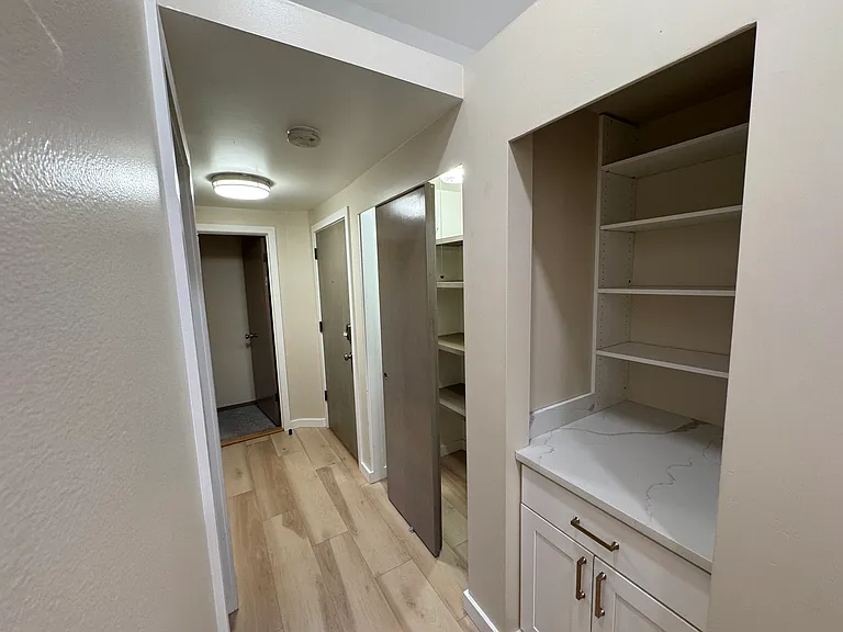 Starting on the left: primary bedroom, back door leading to alley, storage closet, and bookshelf with storage below.