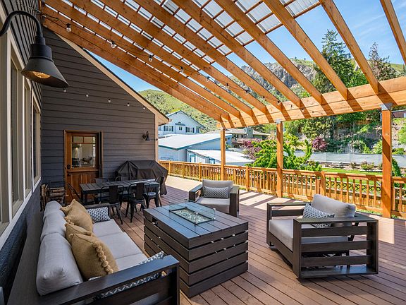 Covered outdoor patio perfect for lounging with sofa comfy chairs, fire table, and propane barbeque.