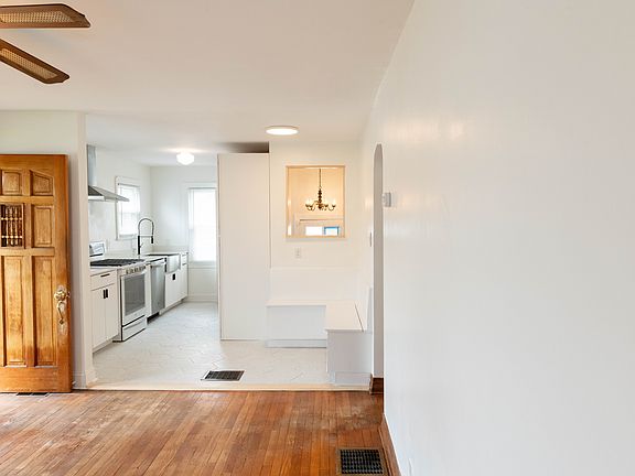 View of living room and kitchen layout, with front door open.