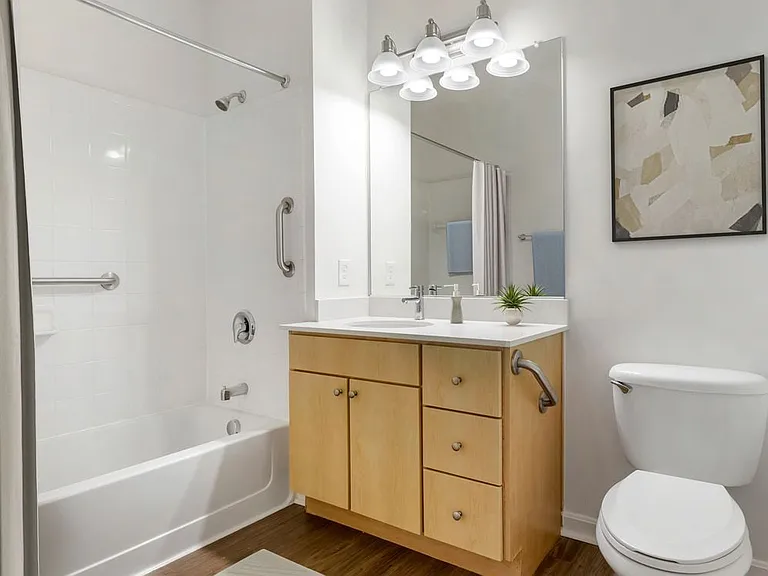 Classic Package III bath with light oak cabinetry, white quartz countertops, and hard surface flooring