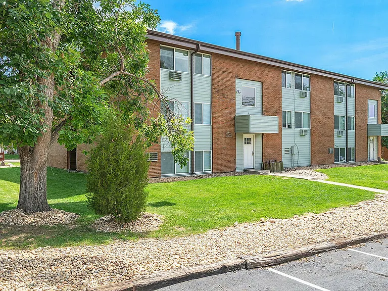 Charming apartment building with brick facade, well-maintained lawns, and mature trees, perfect for serene living.