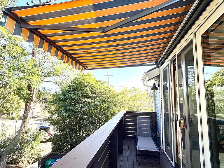 Covered balcony/ patio (with power operated retractable sunshade), lounge chair and bar height chairs for sitting.