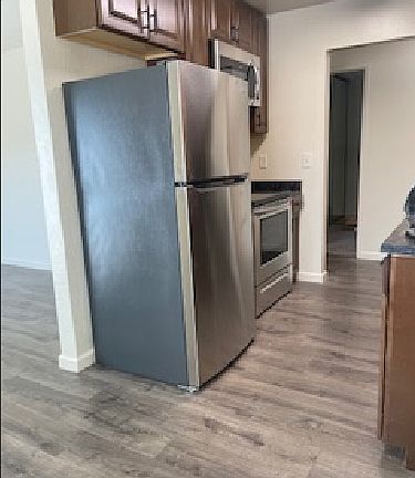 This shows the brand new appliances, cabinets and wood floors. Fridge, stove/oven and built-in microwave.