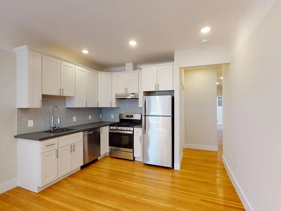 Kitchen with multiple cabinets, refrigerator, stove, range hood, and sink
