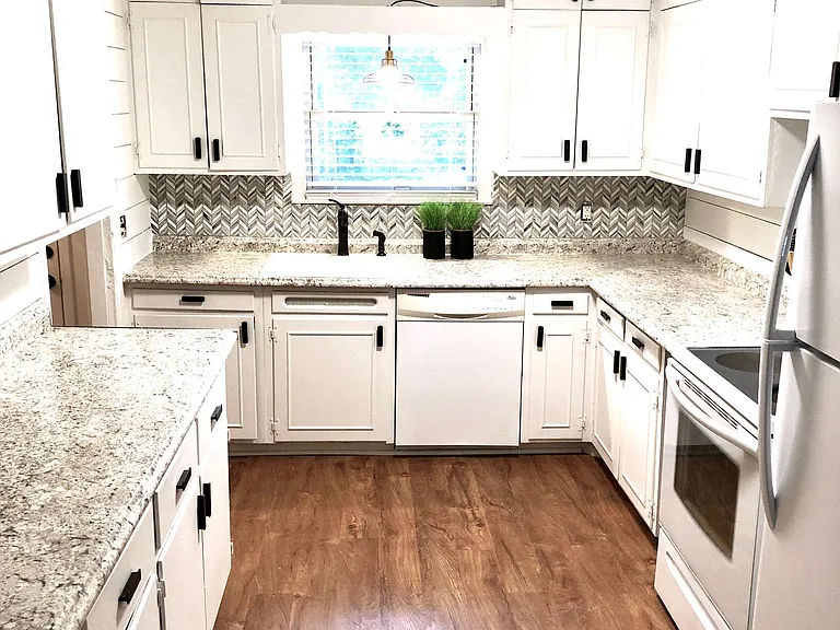 Large renovated kitchen with glass tile backsplash and shiplap walls. New appliances.