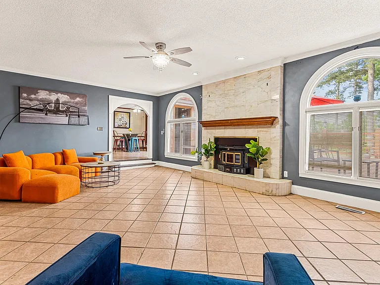 Spacious living room with tile floors, large arched windows, and a statement fireplace, plus an open flow to dining.