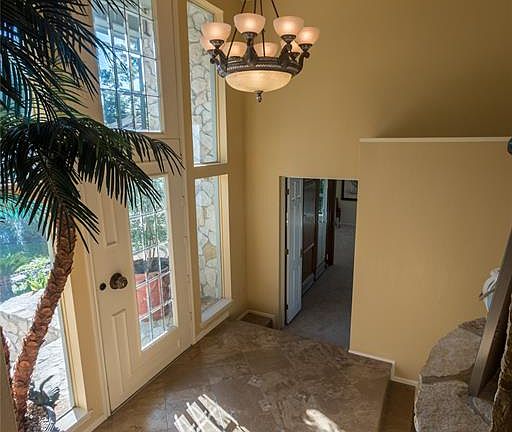 The dramatic entry to this stunning home features stone steps, a high ceiling an elegant chandelier and lots of nature light from the abundant windows.