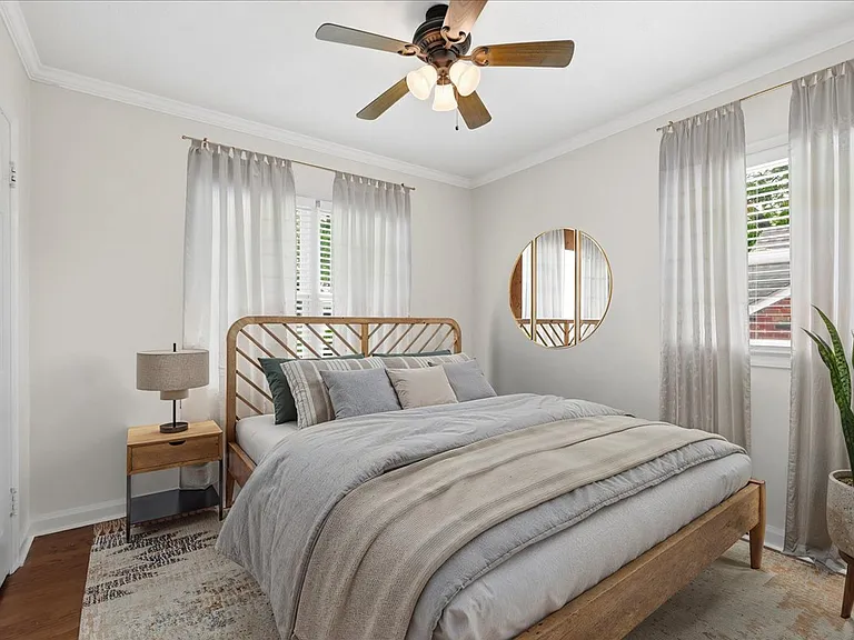 Virtual staging of bedroom 1 with new windows, new window blinds, new interior door, and new doorknob. New trim and fresh paint. Windows face east and south.