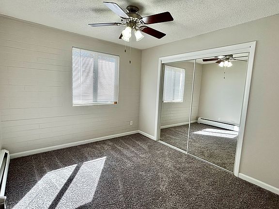 Bright bedroom with cozy carpet, mirrored closet doors, and ceiling fan, perfect for a relaxing retreat.