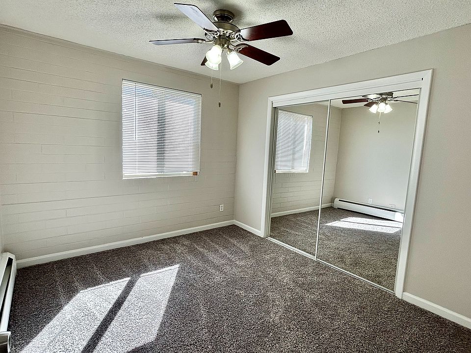 Bright bedroom with cozy carpet, mirrored closet doors, and ceiling fan, perfect for a relaxing retreat.