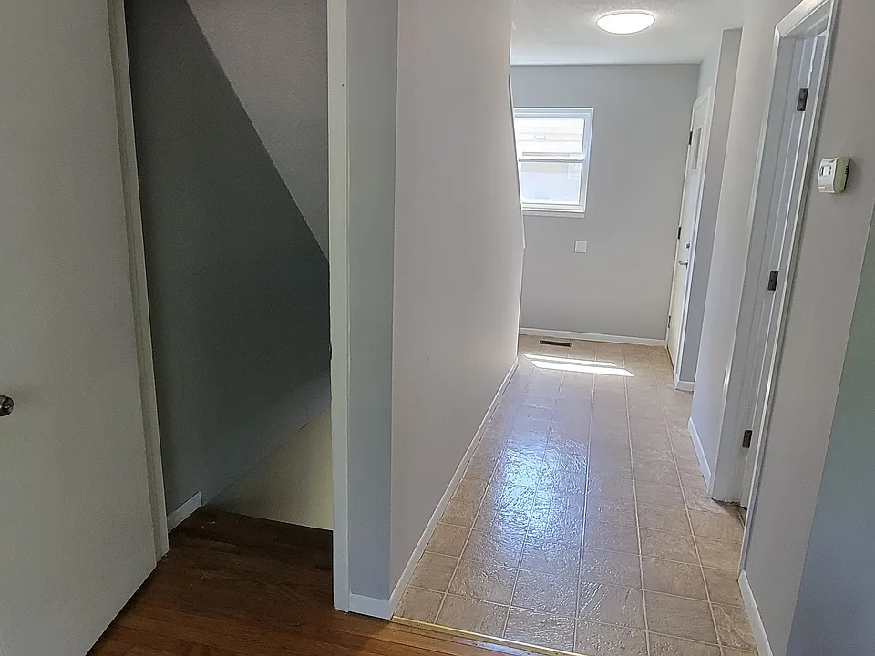 Standing in the living room, looking towards the front door and basement door on the left. Main floor bath is also in the hall on the right.