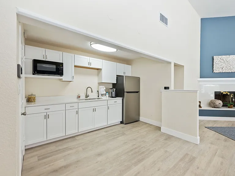 Modern kitchen with sleek white cabinetry, stainless steel appliances, and elegant wood flooring opening to a stylish living area with a cozy fireplace.
