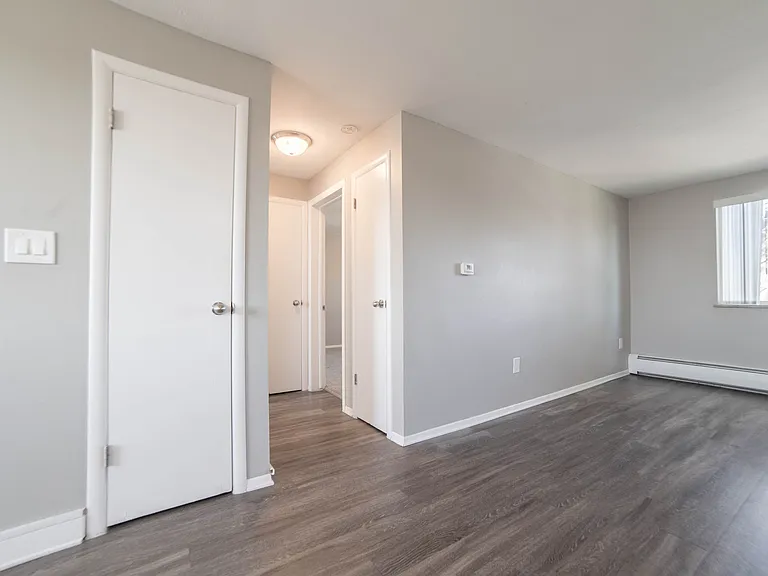 Bright and airy living space with modern gray flooring, soft gray walls, and a large window for ample natural light.